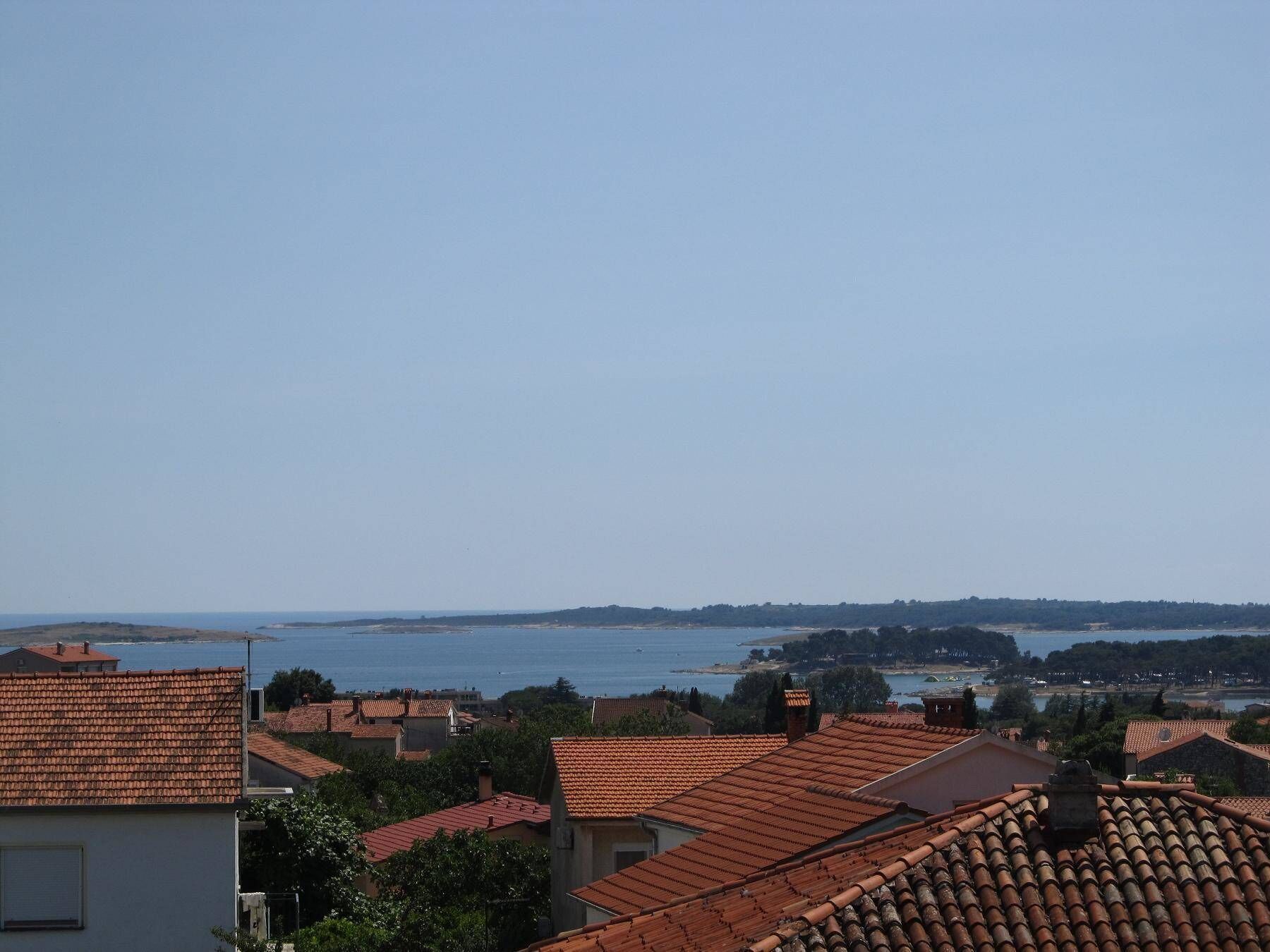 A coastal town with terracotta-roofed buildings and a view of the sea.