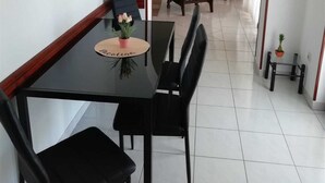 Un'area pranzo con un tavolo nero, sedie nere, una piccola pianta in vaso e un quadro appeso al muro.