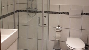 Ein modernes Badezimmer mit einer gläsernen Duschkabine, Toilette und Waschbecken.