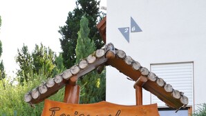 Puinen kyltti, jossa lukee ”Feriendorf”, ja pieni ruukku, jossa on punaisia kukkia.