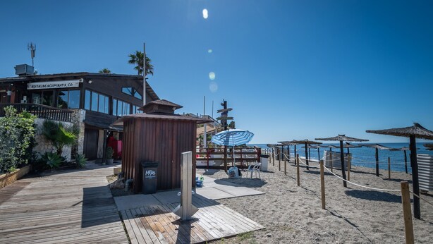 A beachside building with a wooden deck, a sign reading "ROYALBEACHPIERATA.CO", and a view of the ocean. - Outdoors apartment labandera at the gates of Marbella (Mijas Costa)