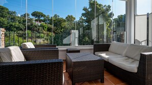 A sunlit balcony with wicker furniture, large windows, and a view of greenery. - Outdoors apartment labandera at the gates of Marbella (Mijas Costa)