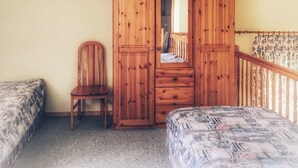 Une chambre à coucher avec une armoire en bois, une chaise et un lit.