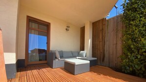 A covered outdoor seating area with a wooden deck, a sofa, and a small table. - Hunsruecklust vacation apartment with e-bike rental (Beltheim)