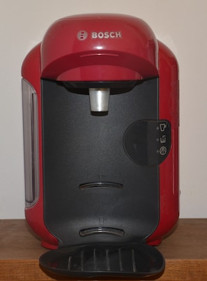Eine rote Bosch Kaffeemaschine mit schwarzem Bedienfeld und einer Kaffeekanne.