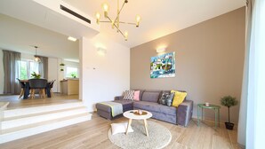 A modern living room with a sectional sofa, a round coffee table, and a dining area with a table and chairs. - Villa Gardena with heated pool (Kvarner - Vrh) (Vrh)