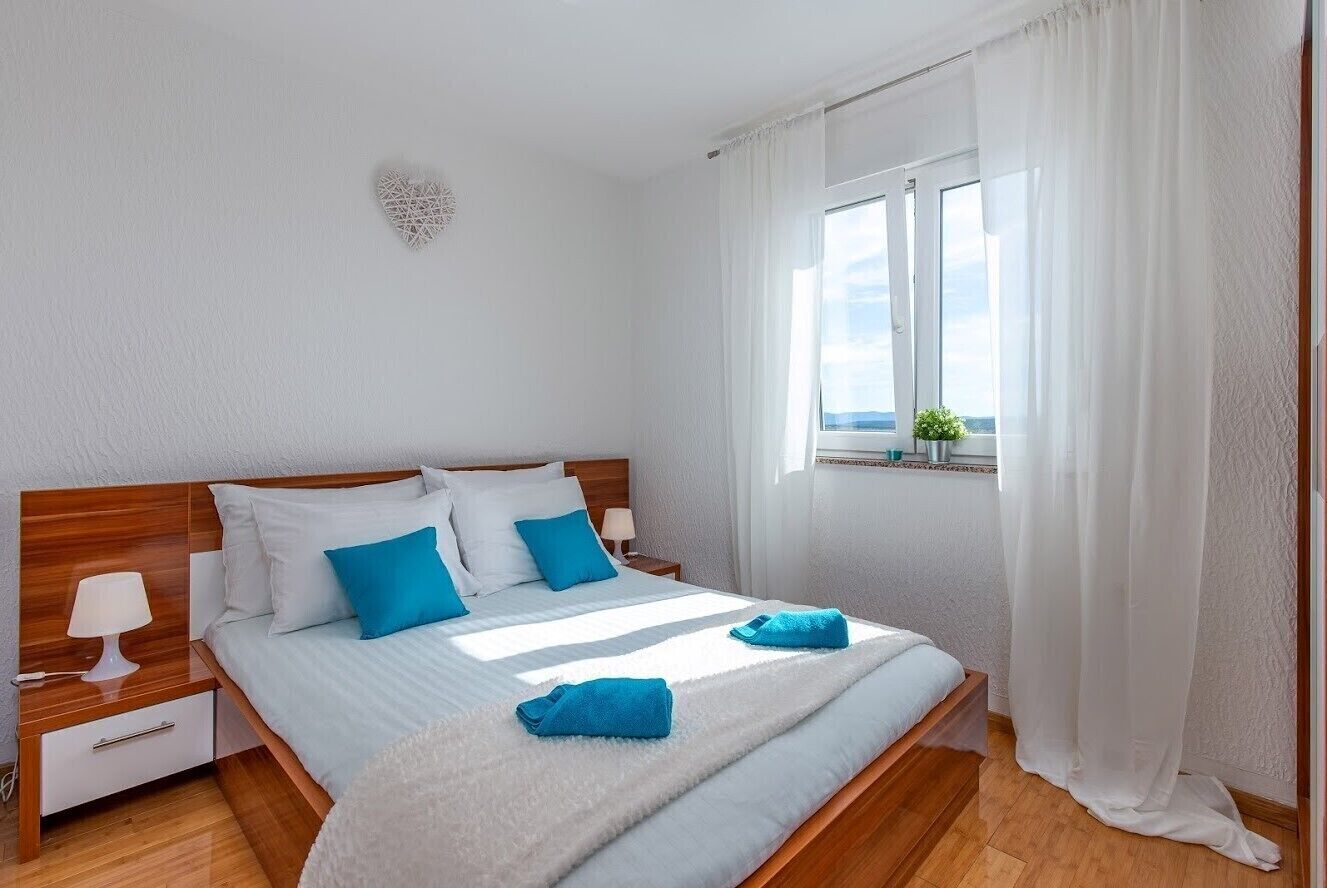 A bedroom with a wooden bed, white walls, and a window with a view.
