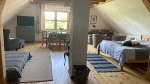 Un dormitorio acogedor en el ático, con suelo de madera, una cama, un escritorio y una mesa de comedor.