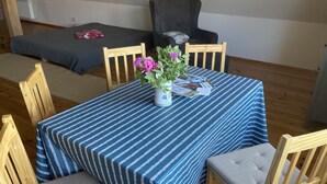 Un comedor con una mesa dispuesta para cuatro personas, con mantel a rayas, sillas de madera y un florero con flores.