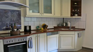 A kitchen with white cabinets, a built-in oven, a coffee maker, and a fruit bowl on the counter. - (g) Roosike vacation in Bacharach-Steeg, modern apartment in the countryside (Bacharach)