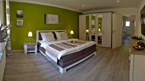 A bedroom with a bed, nightstands, a dresser, a mirror, and a green wall. - (g) Roosike vacation in Bacharach-Steeg, modern apartment in the countryside (Bacharach)