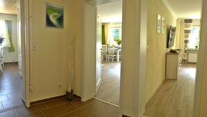 A hallway with a dining area in the background, a painting on the wall, and a potted plant near the entrance. - (g) Roosike vacation in Bacharach-Steeg, modern apartment in the countryside (Bacharach)