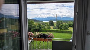 A balcony with a view of a green landscape, including trees and a distant mountain range.