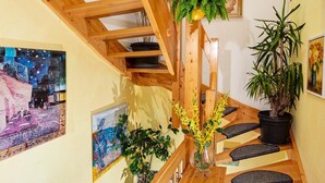 Eine Holztreppe mit Geländer, ein Blumentopf und eine Obstschale auf der Zwischenebene.