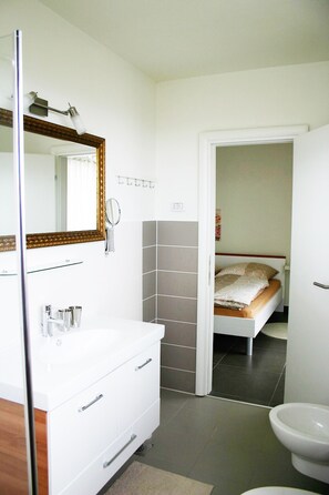 Ein modernes Badezimmer mit einem weißen Waschtisch, einem Spiegel mit goldener Rahmung und einer Toilette.