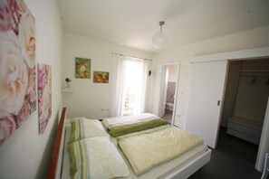 Ein Schlafzimmer mit einem Bett, einem Kleiderschrank und einem durch eine offene Tür einsehbaren Badezimmer.