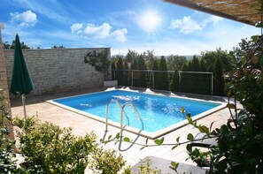 Ein rechteckiger Pool mit einer Steinmauer und einem Metallgeländer.