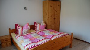 Una cama de madera con un colcha colorida, un armario de madera y una mesita de noche pequeña.