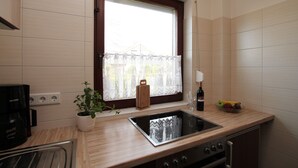 Eine Küche mit Fenster, Spüle, Kaffeemaschine, einer Weinflasche und einer Obstschale.