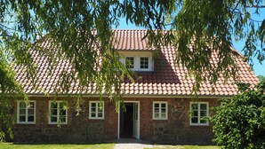 A two-story brick building with a red-tiled roof, a central entrance, and a paved driveway leading to the front door. - Villa holiday Stintenburg island in the Biosphere (Zarrentin am Schaalsee OT Stintenburg)