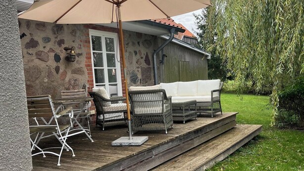 A patio area with outdoor furniture, a stone wall, and a red-tiled roof. - Villa holiday Stintenburg island in the Biosphere (Zarrentin am Schaalsee OT Stintenburg)