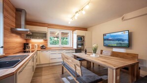 A modern kitchen with wooden cabinetry, a built-in microwave, and a large window. - SKI IN - SKI OUT at the Eichenhof ski lifts (St.Johann In Tirol)