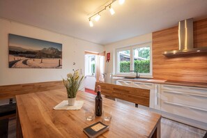 Une cuisine moderne avec des meubles en bois, une hotte de cuisine en acier inoxydable et une grande fenêtre offrant une vue sur la verdure environnante.