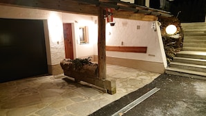 A stone pathway leading to a building with a wooden bench and a hanging light fixture. - SKI IN - SKI OUT at the Eichenhof ski lifts (St.Johann In Tirol)