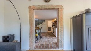 Un couloir avec une arche en pierre menant à une cuisine.