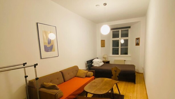 Un espai habitable compacte amb un sofà, una taula petita i una cadira. Hi ha una finestra amb vista a l'exterior.