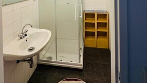 Bany amb dutxa tancada amb vidre, un lavabo i un mirall.