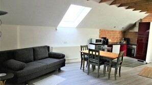 A loft-style apartment with a dining area, kitchenette, and a gray sofa. - Detached holiday home, apartment 1 / for 2-4 persons, W-LAn free (Mehren/Daun)