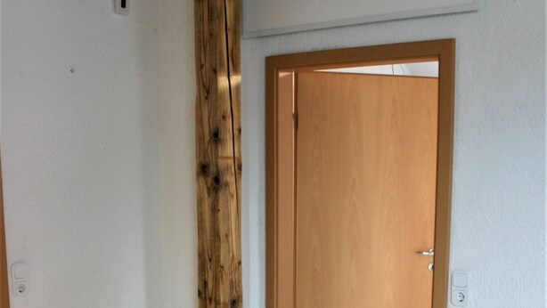 A room with a wooden beam ceiling, a wooden door, and a light-colored floor. - Detached holiday home, apartment 1 / for 2-4 persons, W-LAn free (Mehren/Daun)