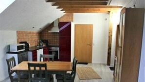 A compact kitchen with a dining table and chairs, a microwave, and a red cabinet. - Detached holiday home, apartment 1 / for 2-4 persons, W-LAn free (Mehren/Daun)
