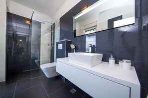 A modern bathroom with a glass shower enclosure, a white sink, and a large mirror. - Villa Red with pool, seaview (Makarska)