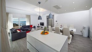Ein modernes Wohnzimmer mit Sofa, Essbereich und Kücheninsel.