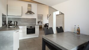 Una cucina moderna con mobili bianchi, elettrodomestici in acciaio inossidabile e un'area pranzo con tavolo e sedie.
