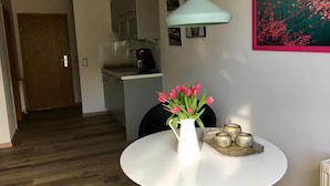 Une cuisine moderne avec des meubles blancs, une machine à café et un luminaire suspendu.