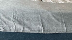Un lit avec une couette à rayures grises et blanches, deux coussins à motifs floraux et une tête de lit sombre.