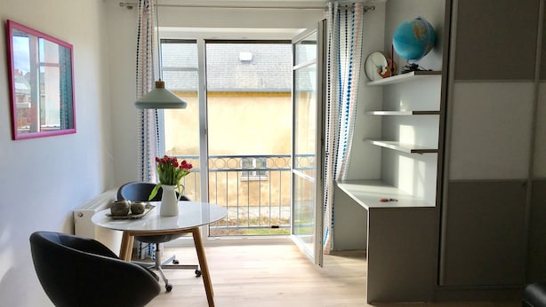Un salon moderne avec une table à manger, une chaise noire, un globe terrestre et une vue sur l’extérieur.