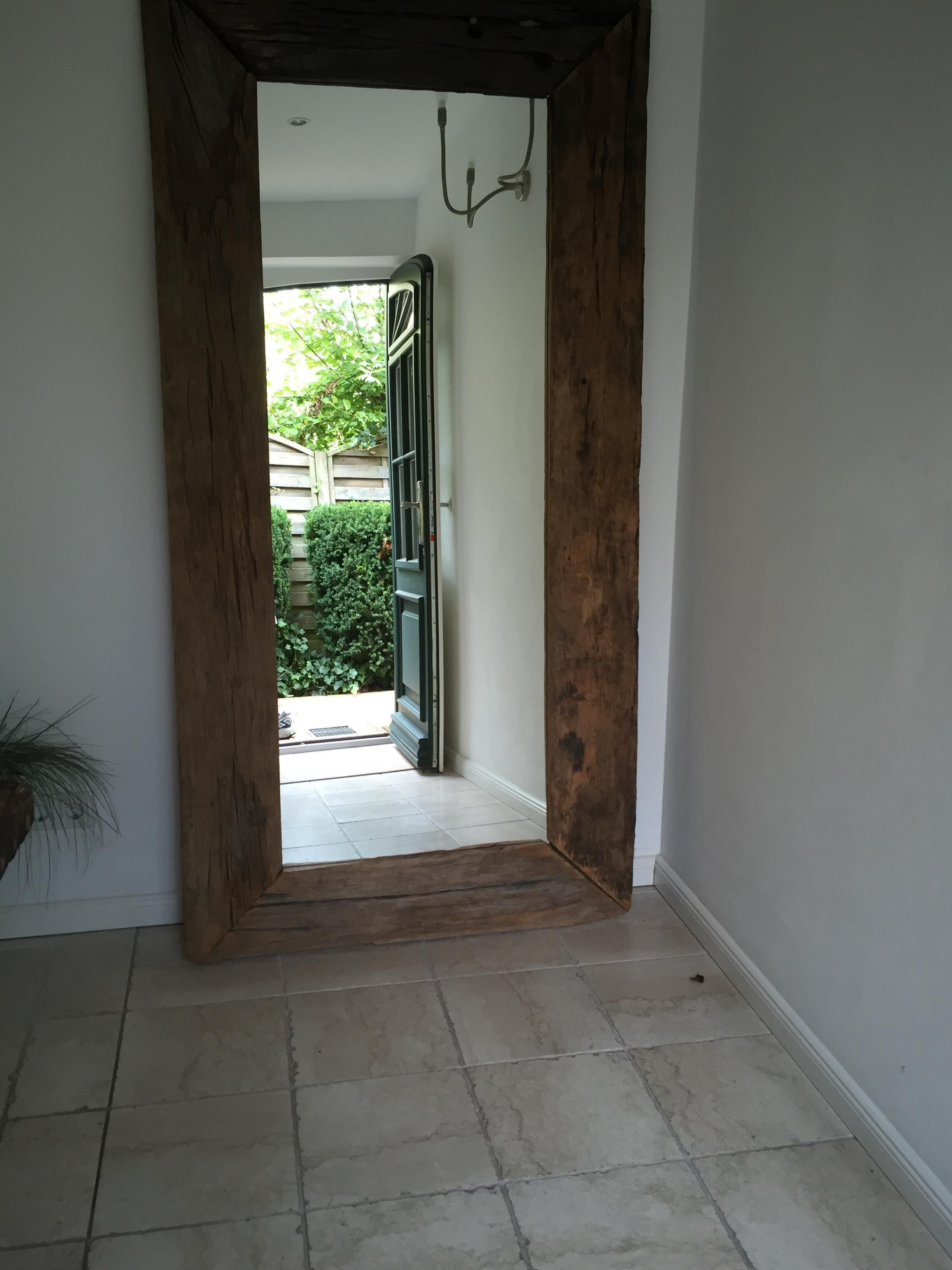 A hallway with a wooden door leading to a garden area.