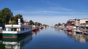 En flod med båtar förtöjda längs stränderna, omgiven av byggnader och träd.