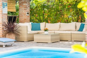 A poolside area with a wicker sofa, a small table with a vase, and a potted plant. - APARTMENTS JURIĆ WITH SWIMMING POOL, 15 MIN. TO THE CENTER, 5 MIN. TO THE BEACH (RAB)