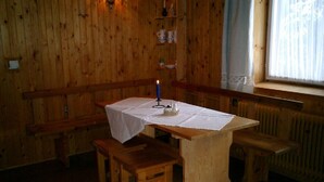 A wooden interior with a table and benches, a window with curtains, and a radiator. - Comfortable, romantic vacation home right at a national park (Jakubovany)