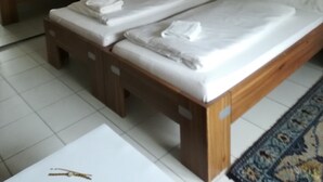 Una habitación de hotel con cama doble, cabecera de madera, candelabro, espejo, televisor y una decoración de amapola roja en la pared.
