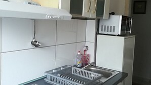 Una cocina con armarios blancos, encimera negra, horno empotrado y microondas sobre un estante blanco.