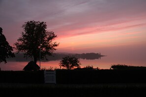 A sunset over a body of water with trees and a gazebo. - Troense B&B by the sea (Svendborg)