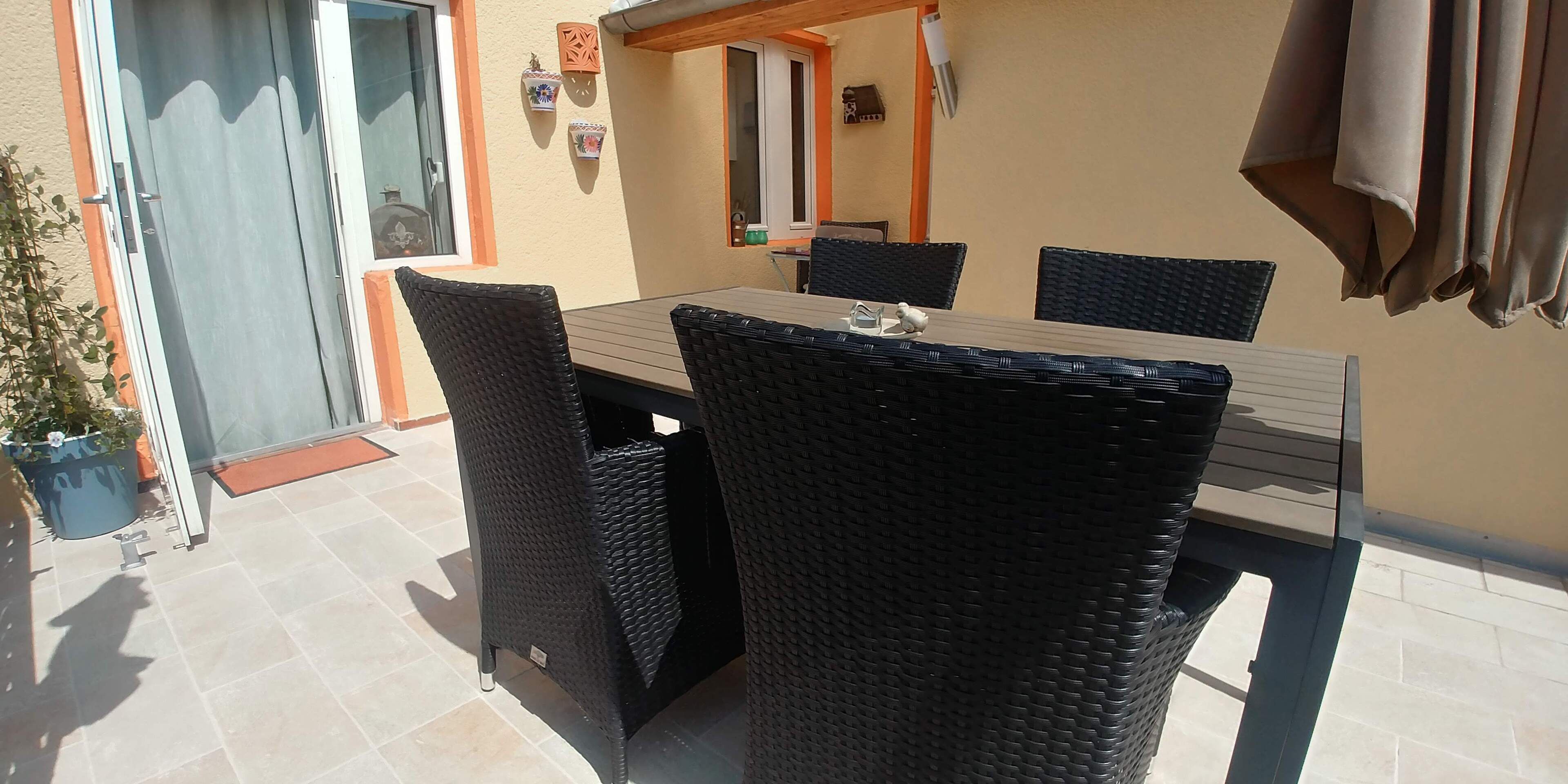 A patio with a table and chairs, a sliding glass door, and a small potted plant.