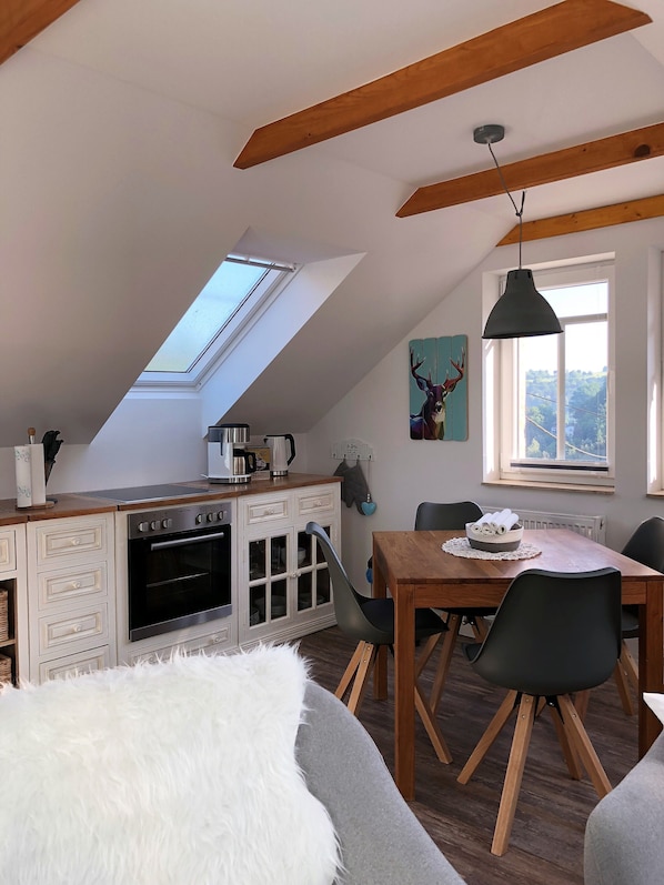 A modern kitchen with a skylight, wooden beams, and a dining area with a table and chairs. - NEW 2018 fully renovated apartment right on the famous Malerweg (Pfaffendorf)
