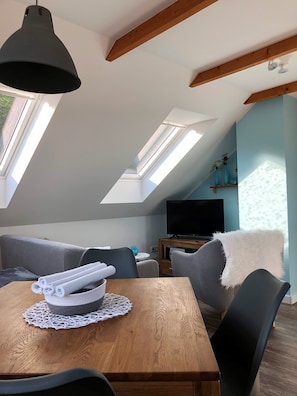 A modern loft bedroom with skylights, a wooden dining table, and a gray sofa. - NEW 2018 fully renovated apartment right on the famous Malerweg (Pfaffendorf)